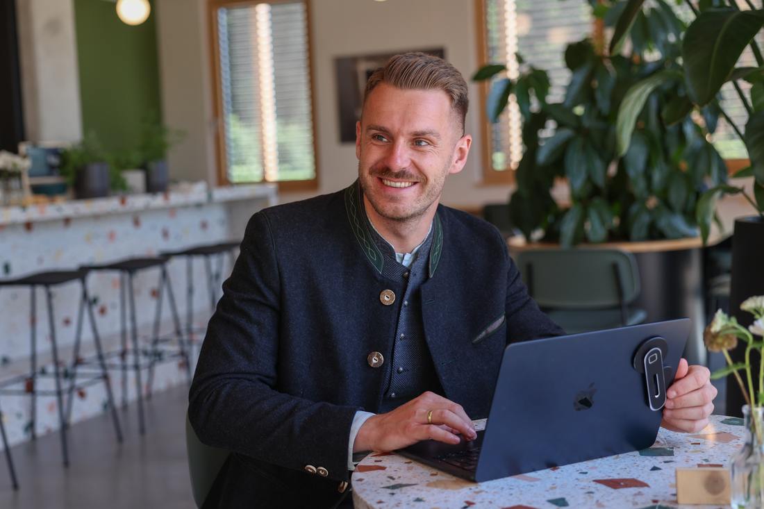 Dominik Sinzinger im Trachtenjanker am Laptop – Beratung mit regionaler Handschrift